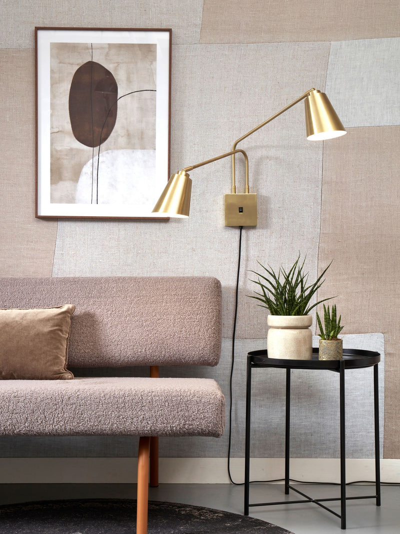 Wandleuchte It’s about RoMi Bremen 2-armig mit goldfarbenen Schirmen und quadratischer Wandplatte, montiert über einem Sofa.
