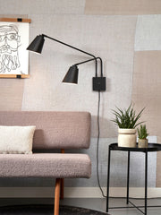 Wandleuchte It's about RoMi Bremen 2-armig in Schwarz aus Eisen, mit zwei schwenkbaren Schirmen über einem Sofa montiert.