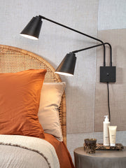Wandleuchte It's about RoMi Bremen 2-armig in Schwarz mit zwei verstellbaren Eisenschirmen über einem Rattan-Bett.