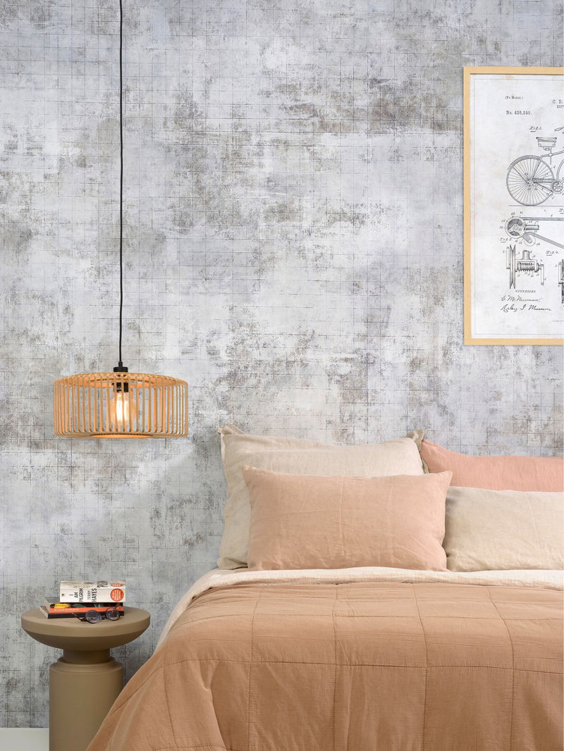 Gesamtansicht eines Schlafzimmers: Hängeleuchte Bromo aus Bambus in Natur/Schwarz über einem Beistelltisch, davor ein Bett mit beige-rosé Bettwäsche.