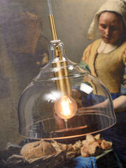 Hängeleuchte Brussels von RoMi mit transparentem Glasschirm und goldener Messingfassung, eingeschaltet über dem Esstisch.