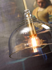 Hängeleuchte „It's about RoMi Brussels“ aus transparentem Glas mit goldfarbener Metallfassung, Detailansicht der Glühlampe.