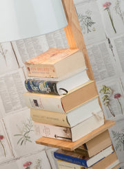 Stehleuchte "It's about RoMi Cambridge" mit weißem Lampenschirm und Holzständer, daran eine Bücherablage mit Bücherstapel.