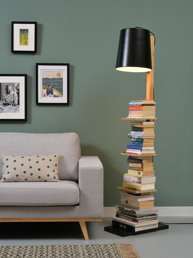 Stehleuchte "It's about RoMi Cambridge" mit schwarzem Schirm, Holzstab und Bücherablage in einem Wohnzimmer.