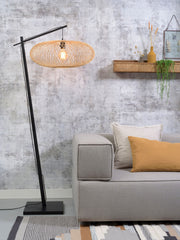 Stehleuchte Cango von Good&Mojo mit ovalem Bambusgeflecht-Schirm und schwarzem Standfuß, neben einem Sofa.