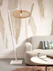 Stehleuchte Cango von Good&Mojo mit geflochtenem Bambusschirm in Natur und weißem Gestell, neben einem Sofa aufgestellt.