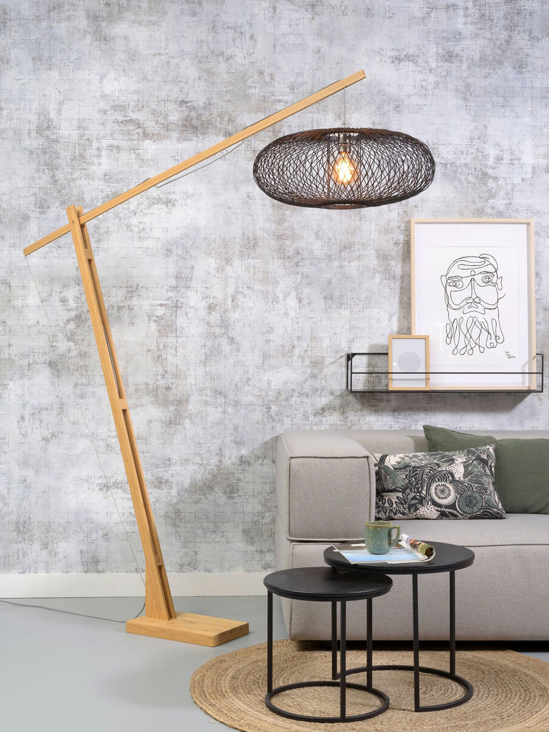 Good&Mojo Stehleuchte Cango mit schwarzem Geflecht-Schirm und schwenkbarem Bambusarm im Wohnzimmer vor Betonoptik-Wand.