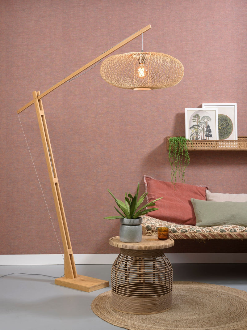 Stehleuchte Cango von Good&Mojo mit schräg geneigtem Bambusarm und ovalem Bambusgeflecht-Schirm in Naturtönen vor rosa Wand.