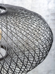 Detailaufnahme des schwarzen Drahtgeflechts der Stehleuchte Good&Mojo Cango mit gewölbter Form, durch die eine Glühlampe schimmert.