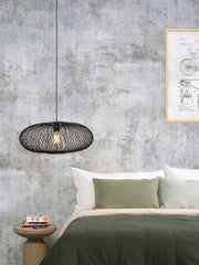 Schwarze Hängeleuchte Cango von Good&Mojo mit ovalem Bambusgeflecht über einem Bett in einem Schlafzimmer mit Betonoptik.