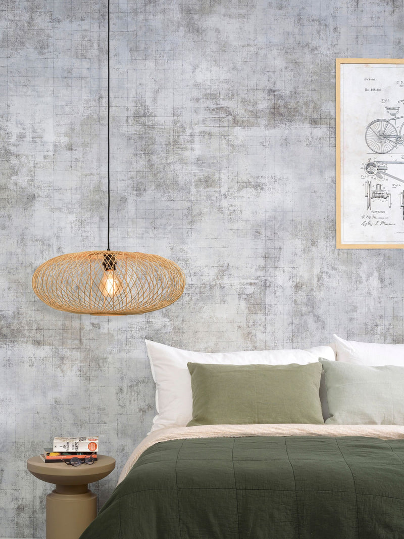 Hängeleuchte Cango aus Bambus in Natur mit schwarzem Kabel, über einem Bett mit grünen Textilien hängend.