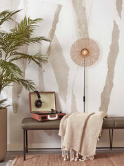 Good&Mojo Wandleuchte Cango aus Bambus und Eisen an einer Wand über einer Sitzbank, mit Plattenspieler und Plaid.