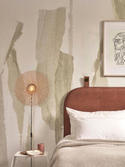 Good&Mojo Wandleuchte Cango aus Bambus und Eisen neben einem Bett mit braunem Lederkopfteil und Wandbild.