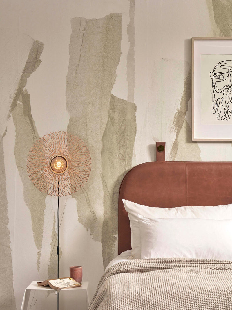 Good&Mojo Wandleuchte Cango aus Bambus und Eisen neben einem Bett mit braunem Lederkopfteil und Wandbild.