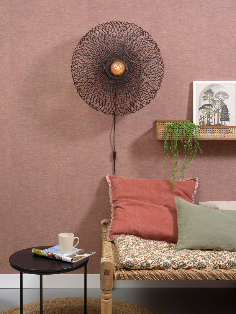 Gesamtansicht der schwarzen Good&Mojo Wandleuchte Cango Bambus Ø 60 cm mit kreisrundem Geflecht über einem Sofa.