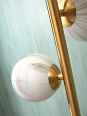 Detailansicht der Stehleuchte It's about RoMi Carrara in Gold mit weiß-grau marmorierten Glaskugeln am goldenen Metallstab.