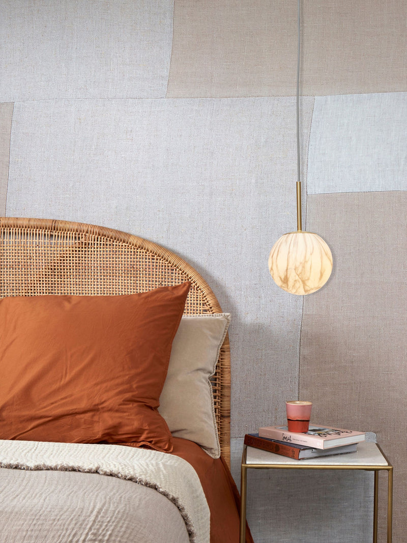RoMi Hängeleuchte Carrara in Gold/Rauchglas mit Marmordruck, kugelförmig, an goldener Stange über einem Bett.