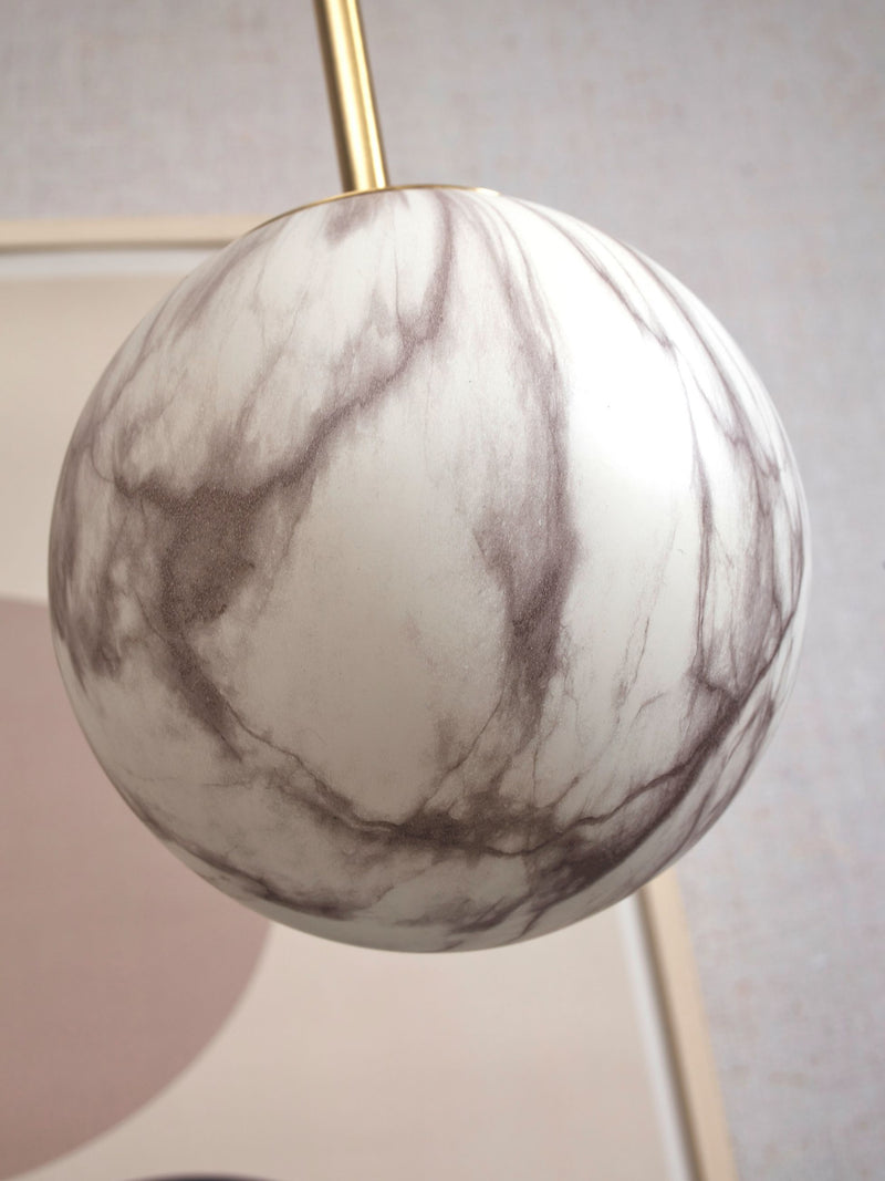 It’s about RoMi Hängeleuchte Carrara: Detailansicht der Glaskugel mit Marmordruck in Weiß und Grau sowie goldener Stange.