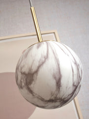 RoMi Hängeleuchte Carrara: Kugelförmiger Glasschirm in Marmoroptik mit grau-weißen Adern, goldene Stange.