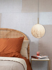 Hängeleuchte It's about RoMi Carrara mit marmoriertem Glasschirm über einem Bett mit Rattan-Kopfteil.