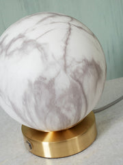 Detailansicht der Tischleuchte It's about RoMi Carrara mit kugelförmigem Marmoroptik-Glasschirm und goldenem Sockel.