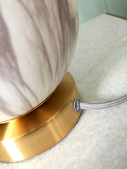 Detailansicht der RoMi Tischleuchte Carrara: goldfarbener Sockel, grau-weiß marmorierter Glasschirm und graues Textilkabel.