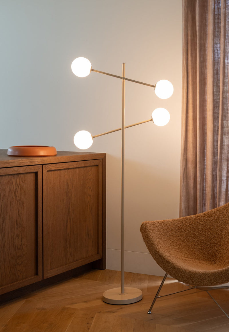 It’s about RoMi Stehleuchte Copenhagen in Beige: Eisengestell mit vier weißen Glaskugeln, im Wohnraum neben einem Sideboard.