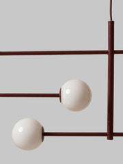 Detailansicht der Pendelleuchte It's about RoMi Copenhagen mit bordeauxrotem Eisengestell und zwei weißen Glaskugeln.