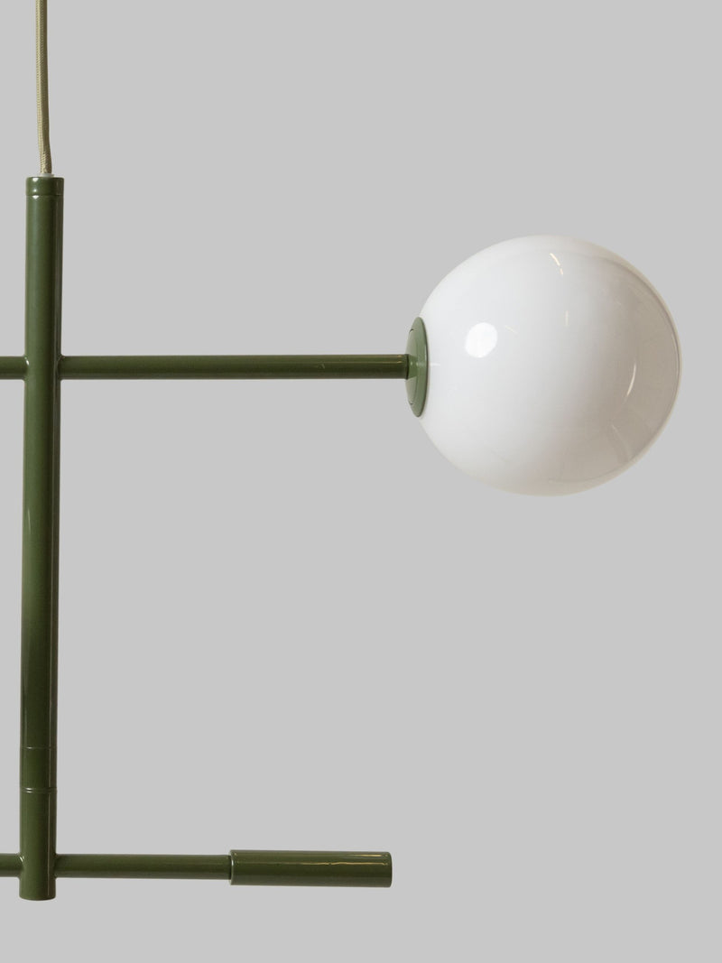 Detailansicht der grünen Pendelleuchte It's about RoMi Copenhagen mit weißem Glasschirm an einem Ausleger aus lackiertem Eisen.