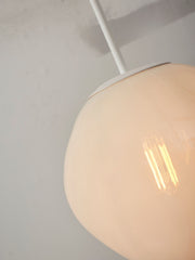 Detailansicht der milchweißen Glas-Hängeleuchte It's about RoMi Helsinki mit weißem Eisengestell und leuchtender Glühlampe.