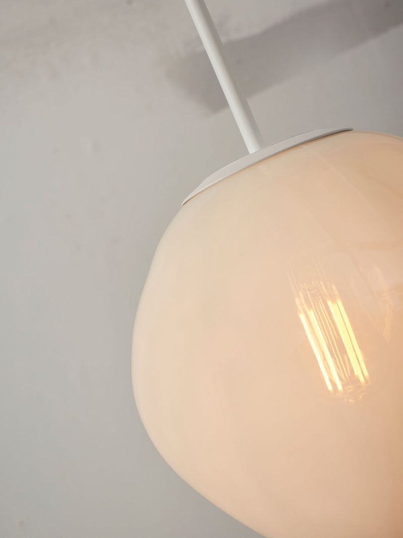 Detailansicht der milchweißen Glas-Hängeleuchte It's about RoMi Helsinki mit weißem Eisengestell und leuchtender Glühlampe.