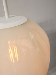Detailaufnahme der milchweißen Glaskugel der Hängeleuchte It's about RoMi Helsinki mit weißem Eisengestell und Lichtreflexen.