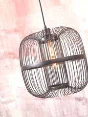Schwarze Hängeleuchte Hokkaido von Good&Mojo mit Drahtgeflecht-Schirm, Glühlampe sichtbar, vor rosa Wand.