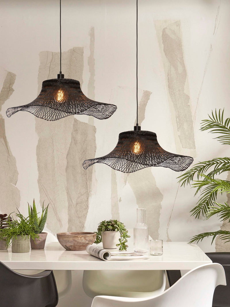 Zwei schwarze Hängeleuchten "Good&Mojo Hängeleuchte Ibiza" mit gewellten Bambusschirmen über einem weißen Esstisch.