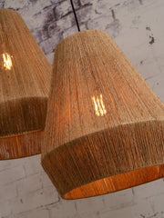 Detailansicht zweier Hängeleuchten Iguazu aus naturfarbener Jute mit schwarzem Kabel, die Glühlampen leuchten warm.