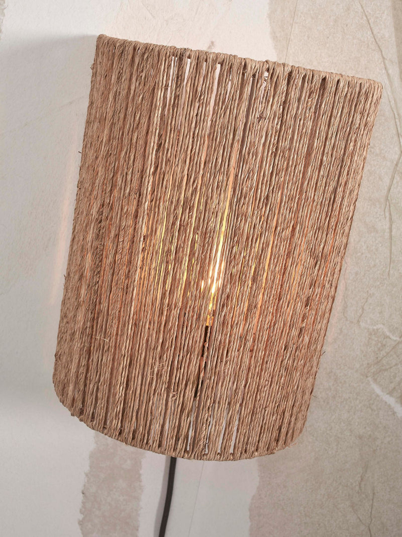 Wandleuchte Iguazu von Good&Mojo mit Halbschirm aus naturfarbener Jute, schräg von vorn, Lichtschein im Inneren.