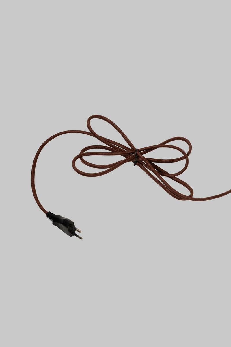 Brauner, textilummantelter Lampenkabel mit Eurostecker, lose zu einer Schlaufe gebunden, auf hellgrauem Hintergrund.