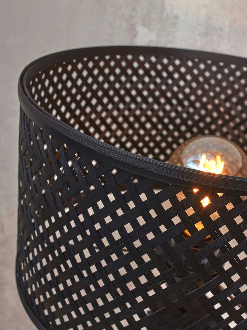 Detailaufnahme des schwarzen Bambusgeflechts der Good&Mojo Stehleuchte Java, durch das eine leuchtende Glühlampe sichtbar ist.