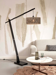 Stehleuchte Java XL von Good&Mojo mit schwarzem Bambusgestell und Bambusschirm in Naturtönen, im Wohnzimmer neben einem Sofa.