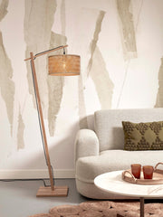 Good&Mojo Stehleuchte Java aus Bambus mit geflochtenem Naturschirm neben einem hellen Sofa mit olivgrünem Kissen.