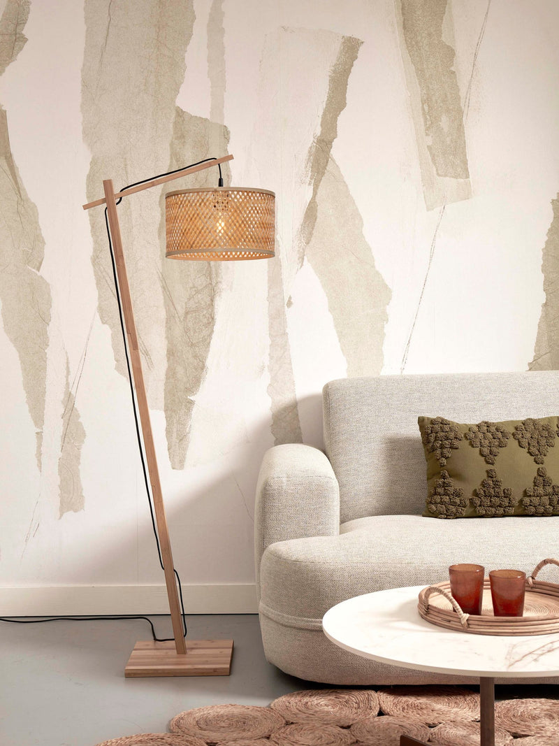 Good&Mojo Stehleuchte Java aus Bambus mit geflochtenem Naturschirm neben einem hellen Sofa mit olivgrünem Kissen.