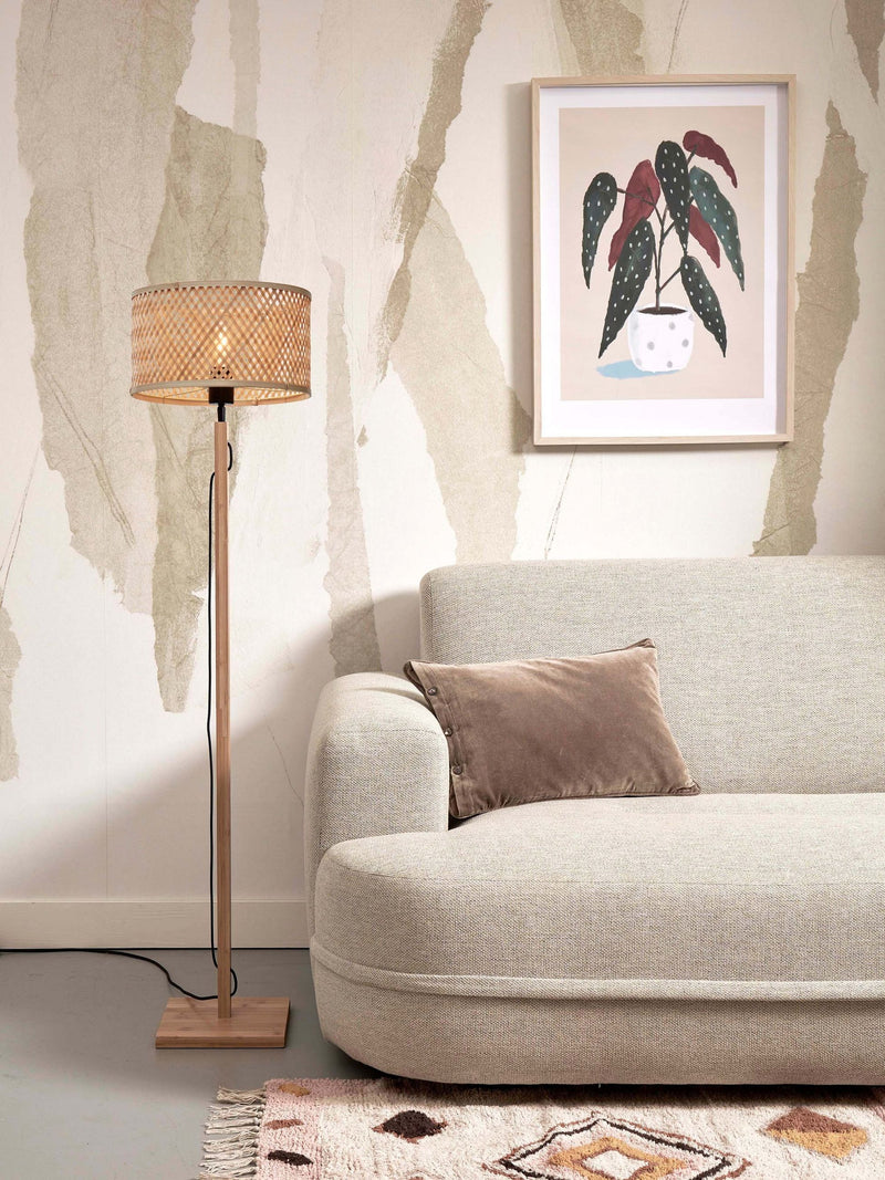 Stehleuchte Java von Good&Mojo mit geflochtenem Bambusschirm und hellem Bambusgestell neben einem Sofa.