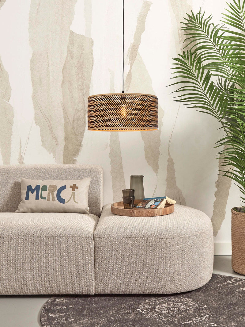 Good&Mojo Hängeleuchte Java aus Bambus über einem beigen Sofa, daneben eine große Zimmerpalme und ein Beistelltablett.