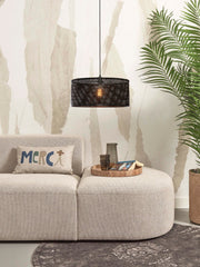 Good&Mojo Hängeleuchte Java in Schwarz hängt über einem Sofa; der geflochtene Bambusschirm lässt warmes Licht durch.