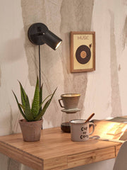 Good&Mojo Wandstrahler Java mit schwarzem Bambusgestell: Gesamtansicht der Wandlampe mit Schalter, daneben Aloe-Pflanze auf Holztisch.