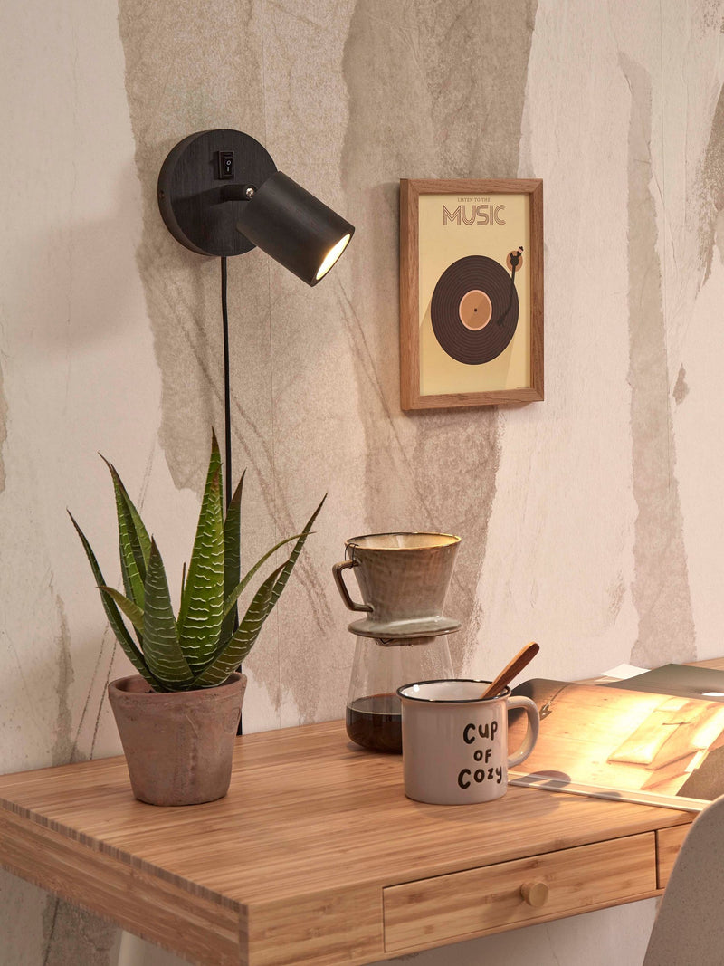 Good&Mojo Wandstrahler Java mit schwarzem Bambusgestell: Gesamtansicht der Wandlampe mit Schalter, daneben Aloe-Pflanze auf Holztisch.