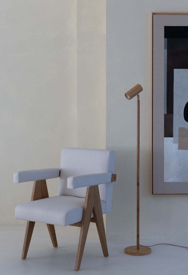 Stehleuchte Java in Natur mit Bambusschirm und Bambusstab neben einem hellen Sessel vor einer Wand mit Kunstwerk