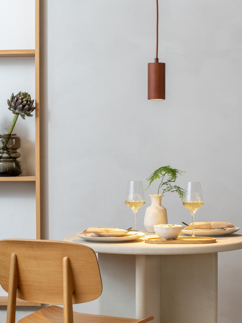 Hängeleuchte Java von Good&Mojo in Braun über einem gedeckten Esstisch mit Weißweingläsern und Holzbrett.