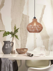 Hängeleuchte Kalahari aus Rattan in Natur über einem weißen Esstisch mit Vase, Holzschale und Karaffe.