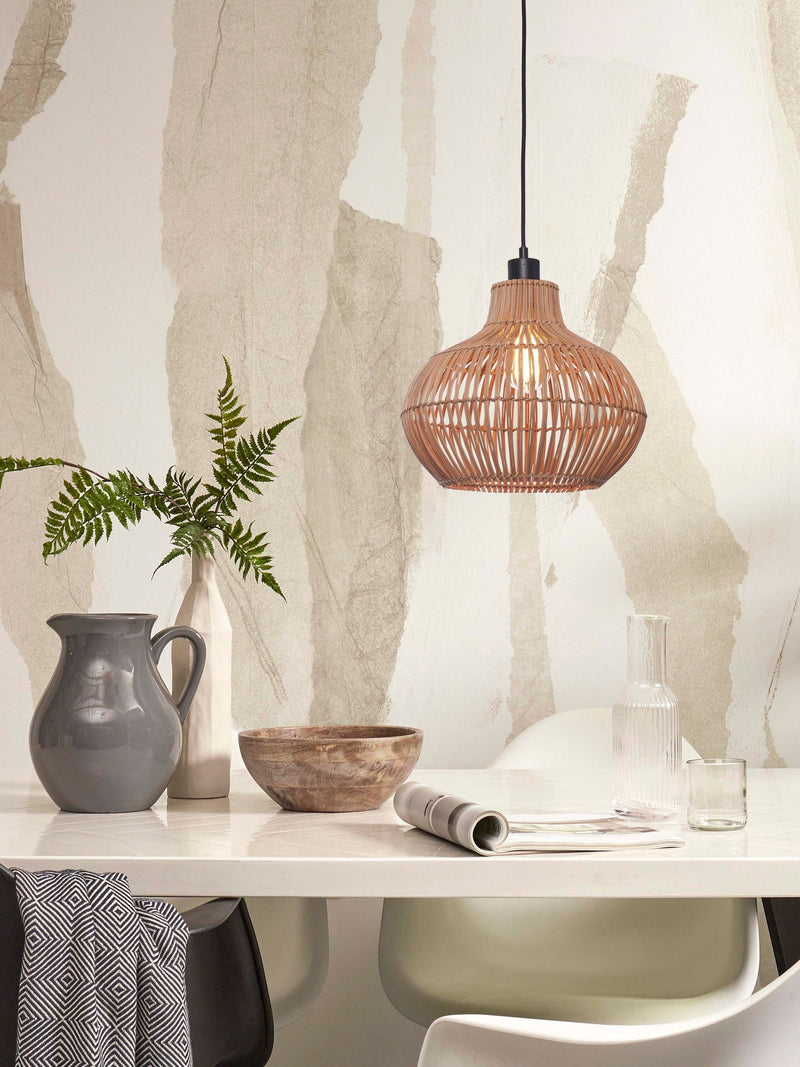 Hängeleuchte Kalahari aus Rattan in Natur über einem weißen Esstisch mit Vase, Holzschale und Karaffe.